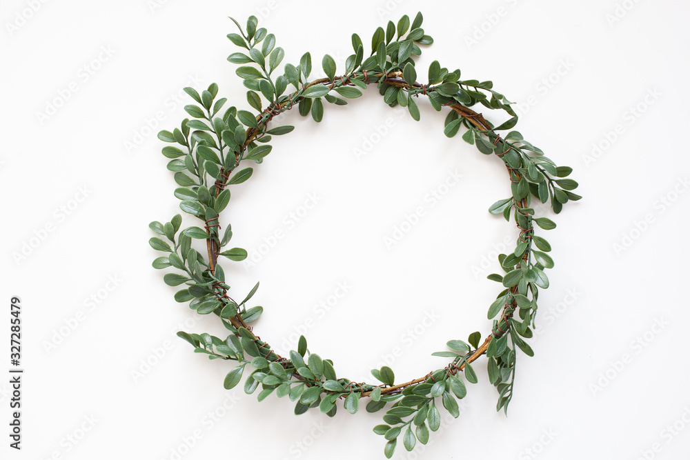 Green wreath with leaves on white background. Wreath made of branches. Flat lay, top view, copy space. Spring composition. Flowers composition. Easter. Boxwood wreath for Christmas. Scandinavian style Green wreath with leaves on white background. Wreath made of branches. Flat lay, top view, copy space. Spring composition. Flowers composition. Easter. Boxwood wreath for Christmas. Scandinavian style