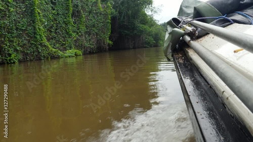 4k video of plastic motorbat sailing on dirty muddy river in tropical jungle forest photo