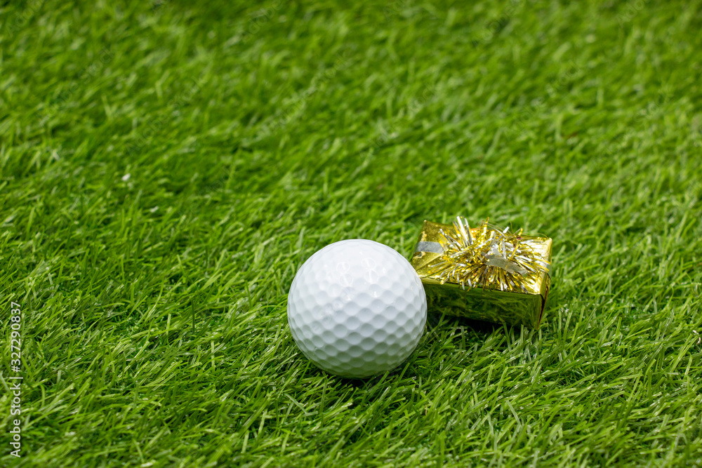 Naklejka premium Golf ball with gift on green grass