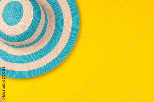 Top view on striped blue hat on yellow background. Concept of beach holiday  sea tour  warm sunny summer. Advertising space