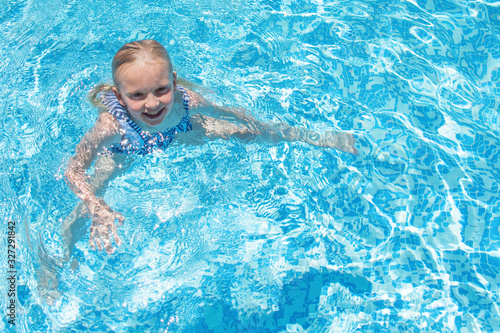 Pretty little girl in swimming pool, summer vacations.