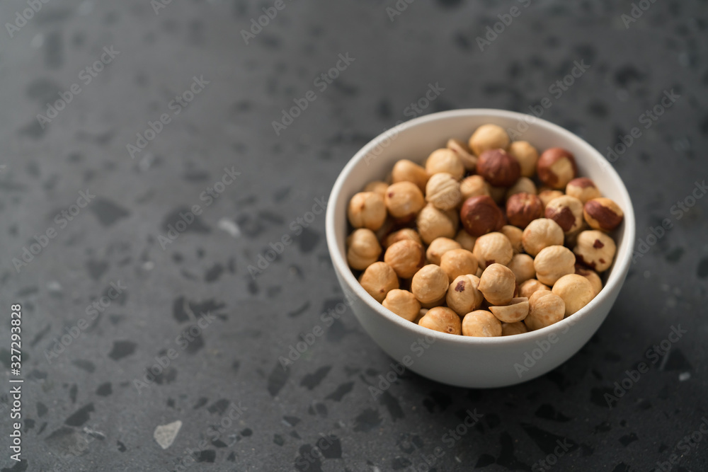 roasted hazelnuts in white bowl on concrete background roasted hazelnuts in white bowl on concrete background