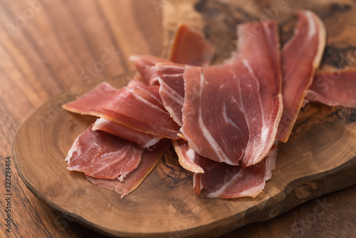 sliced prosciutto on olive wood board