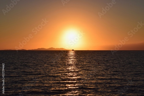 Sunsetting next to a island with a boat caught in-between 