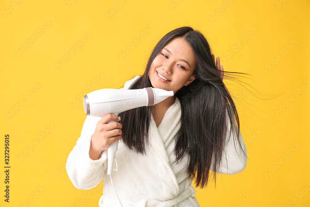 Beautiful Asian woman with hair dryer on color background Beautiful Asian woman with hair dryer on color background