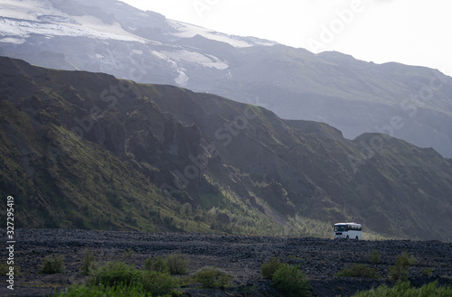 Iceland mountain view with 4x4 big bus with Eyjafjallajokull ob background. Driving tourists