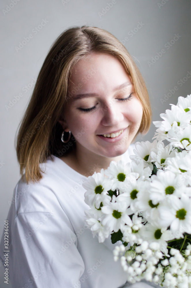 portrait of a young beautiful girl with blond hair and a short haircut with white flowers in her hands on a white background, the concept of beauty and health portrait of a young beautiful girl with blond hair and a short haircut with white flowers in her hands on a white background, the concept of beauty and health