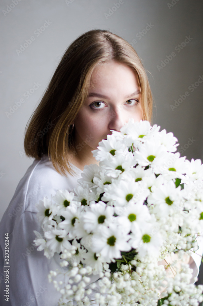 portrait of a young beautiful girl with blond hair and a short haircut with white flowers in her hands on a white background, the concept of beauty and health portrait of a young beautiful girl with blond hair and a short haircut with white flowers in her hands on a white background, the concept of beauty and health