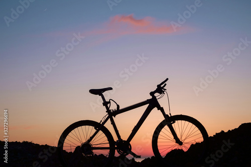 The silhouette of bike on the beach with purple sunset sky background