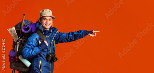 Excited young man backpacker pointing at copy space photo