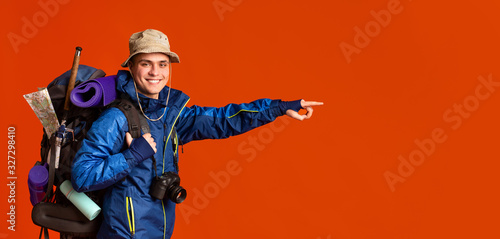 Φωτογραφία Excited young man backpacker pointing at copy space