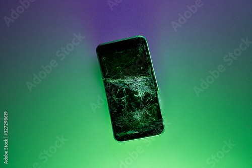 Fototapeta Naklejka Na Ścianę i Meble -  Mobile smartphone with broken screen on green background.