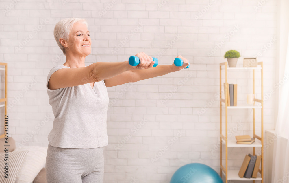 Senior woman exercising with dumbbells at home - obrazy, fototapety, plakaty 