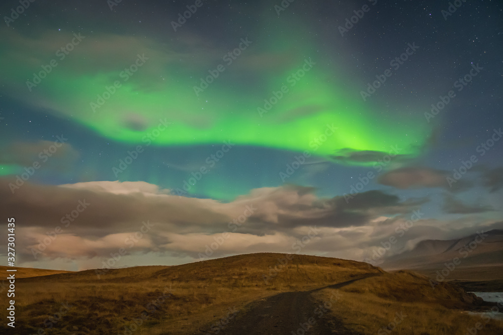 Aurora Borealis in Iceland northern lights bright beams rising in green beams over hiking path