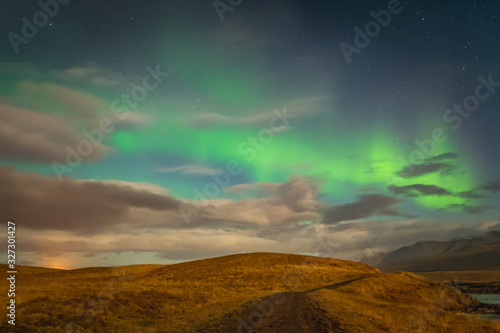 Aurora Borealis in Iceland northern lights bright beams rising green over hiking path