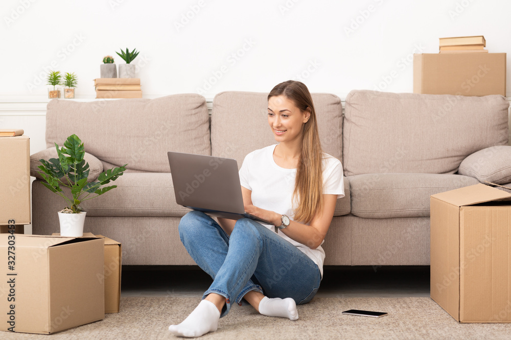 Young smiling woman using laptop in new home Young smiling woman using laptop in new home