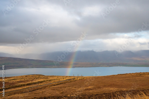 Mountain pass towards Akureyri in Iceland rainbow forming over fjord