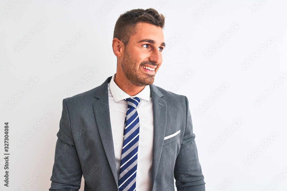 Young handsome business man wearing suit and tie over isolated background looking away to side with smile on face, natural expression. Laughing confident. Young handsome business man wearing suit and tie over isolated background looking away to side with smile on face, natural expression. Laughing confident.