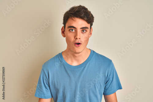 Teenager boy wearing casual t-shirt standing over isolated background afraid and shocked with surprise expression, fear and excited face.
