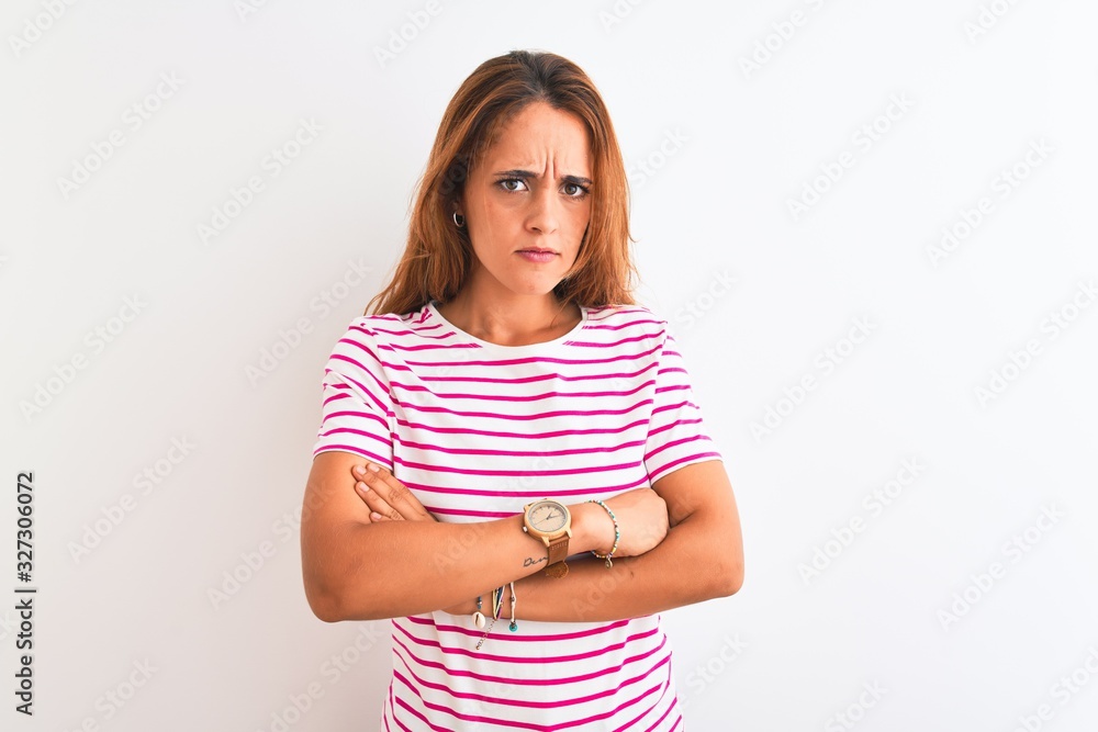 Young redhead woman wearing striped casual t-shirt stading over white isolated background skeptic and nervous, disapproving expression on face with crossed arms. Negative person. Young redhead woman wearing striped casual t-shirt stading over white isolated background skeptic and nervous, disapproving expression on face with crossed arms. Negative person.