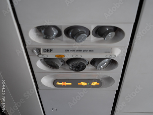 Seatbelt sign lit at the overhead pannel inside an airplane during landing or takeoff