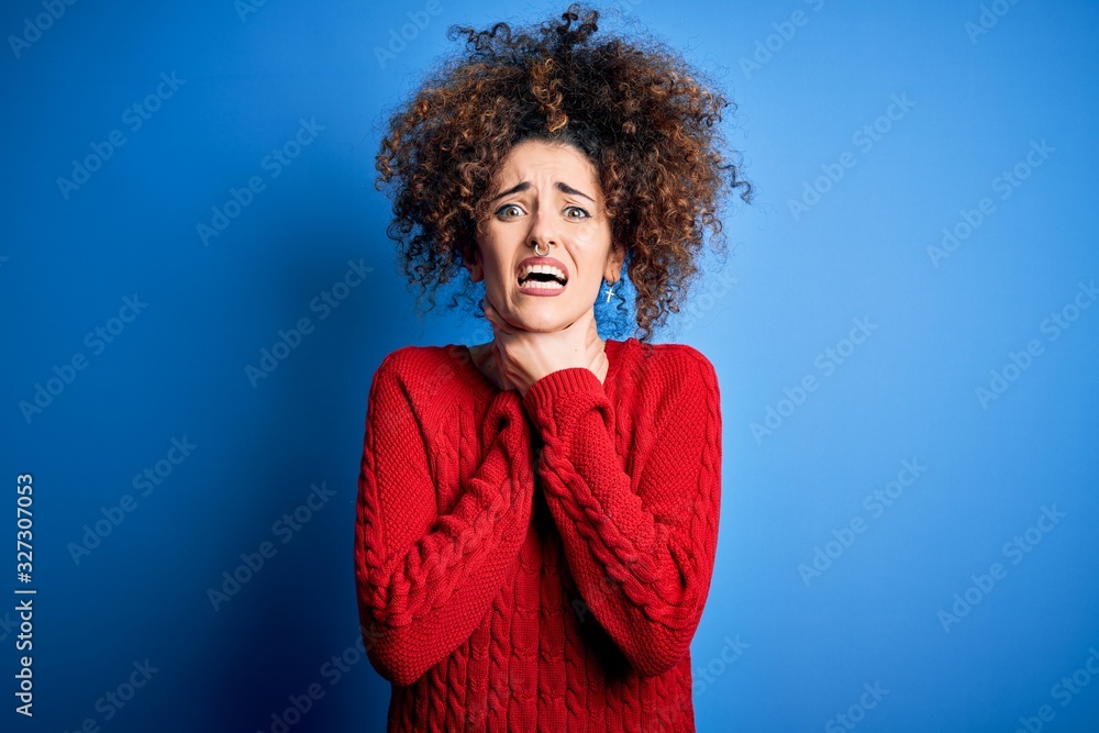 Young beautiful woman with curly hair and piercing wearing casual red sweater shouting and suffocate because painful strangle. Health problem. Asphyxiate and suicide concept. Young beautiful woman with curly hair and piercing wearing casual red sweater shouting and suffocate because painful strangle. Health problem. Asphyxiate and suicide concept.