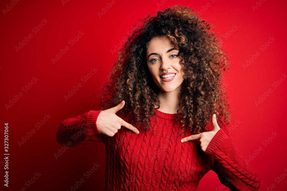 Young beautiful woman with curly hair and piercing wearing casual red sweater looking confident with smile on face, pointing oneself with fingers proud and happy. Young beautiful woman with curly hair and piercing wearing casual red sweater looking confident with smile on face, pointing oneself with fingers proud and happy.