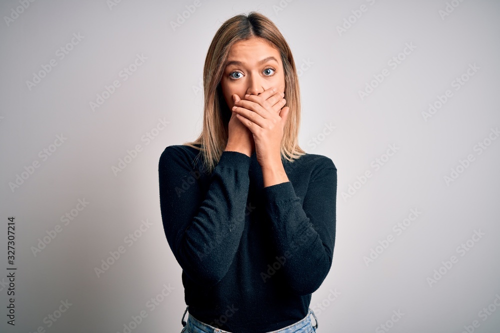 Young beautiful blonde woman with blue eyes standing over white isolated background shocked covering mouth with hands for mistake. Secret concept. Young beautiful blonde woman with blue eyes standing over white isolated background shocked covering mouth with hands for mistake. Secret concept.