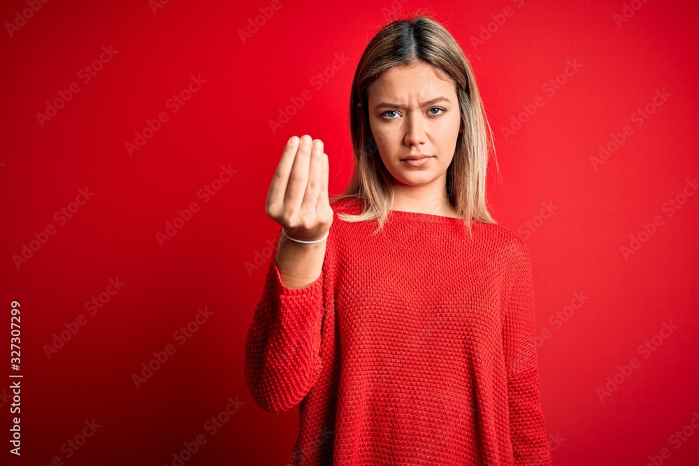 Young beautiful blonde woman wearing casual sweater over red isolated background Doing Italian gesture with hand and fingers confident expression Young beautiful blonde woman wearing casual sweater over red isolated background Doing Italian gesture with hand and fingers confident expression