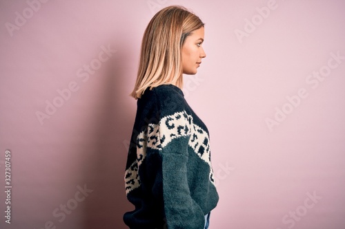 Young beautiful blonde woman wearing fashion sweater over pink isolated background looking to side, relax profile pose with natural face with confident smile.