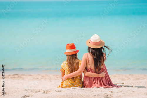 Beautiful mother and daughter at the beach enjoying summer vacation. photo