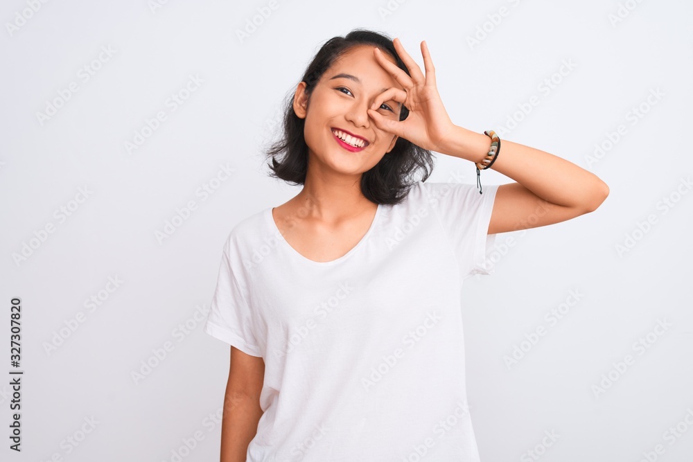 Young chinese woman wearing casual t-shirt standing over isolated white background doing ok gesture with hand smiling, eye looking through fingers with happy face. Young chinese woman wearing casual t-shirt standing over isolated white background doing ok gesture with hand smiling, eye looking through fingers with happy face.