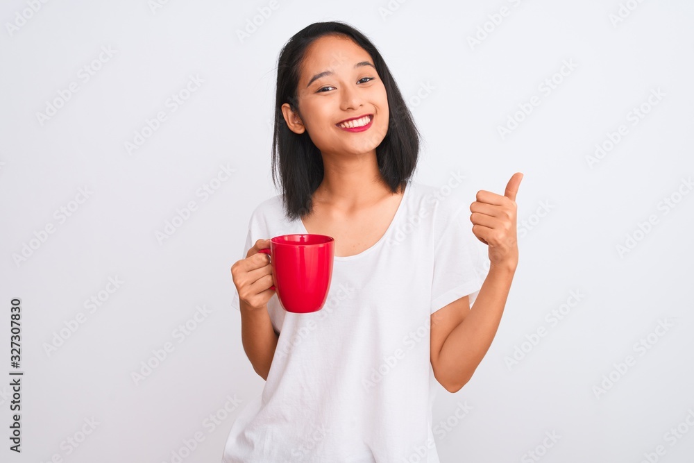 Young beautiful chinese woman drinking cup of coffee over isolated white background happy with big smile doing ok sign, thumb up with fingers, excellent sign Young beautiful chinese woman drinking cup of coffee over isolated white background happy with big smile doing ok sign, thumb up with fingers, excellent sign