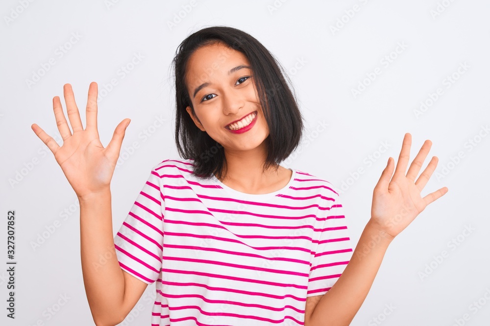 Young chinese woman wearing striped t-shirt standing over isolated white background showing and pointing up with fingers number ten while smiling confident and happy. Young chinese woman wearing striped t-shirt standing over isolated white background showing and pointing up with fingers number ten while smiling confident and happy.