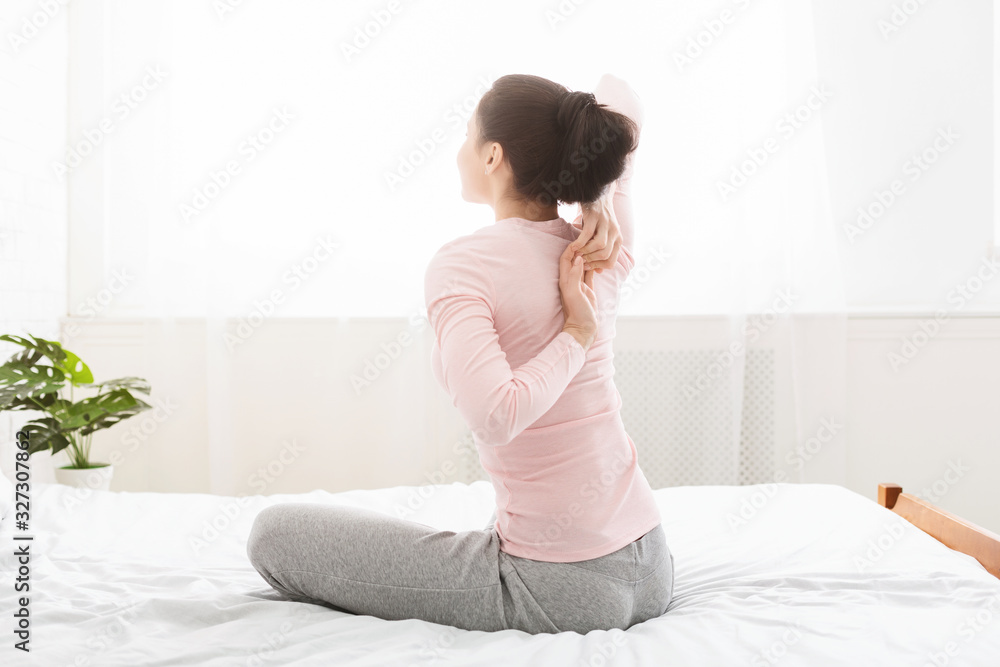 Young yoga woman making hands lock behind the back in bed Young yoga woman making hands lock behind the back in bed