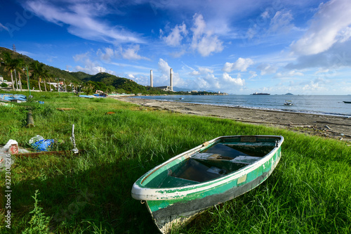 A boat lay on beach under a blue sky white clouds