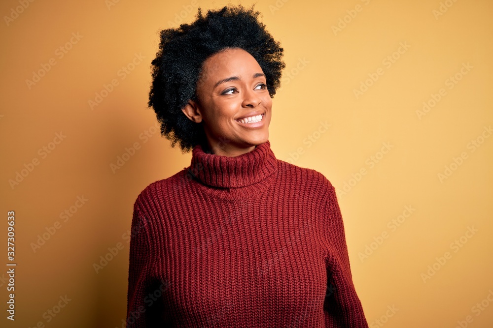 Young beautiful African American afro woman with curly hair wearing casual turtleneck sweater looking away to side with smile on face, natural expression. Laughing confident. Young beautiful African American afro woman with curly hair wearing casual turtleneck sweater looking away to side with smile on face, natural expression. Laughing confident.