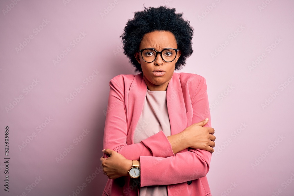 Young beautiful African American afro businesswoman with curly hair wearing pink jacket shaking and freezing for winter cold with sad and shock expression on face
