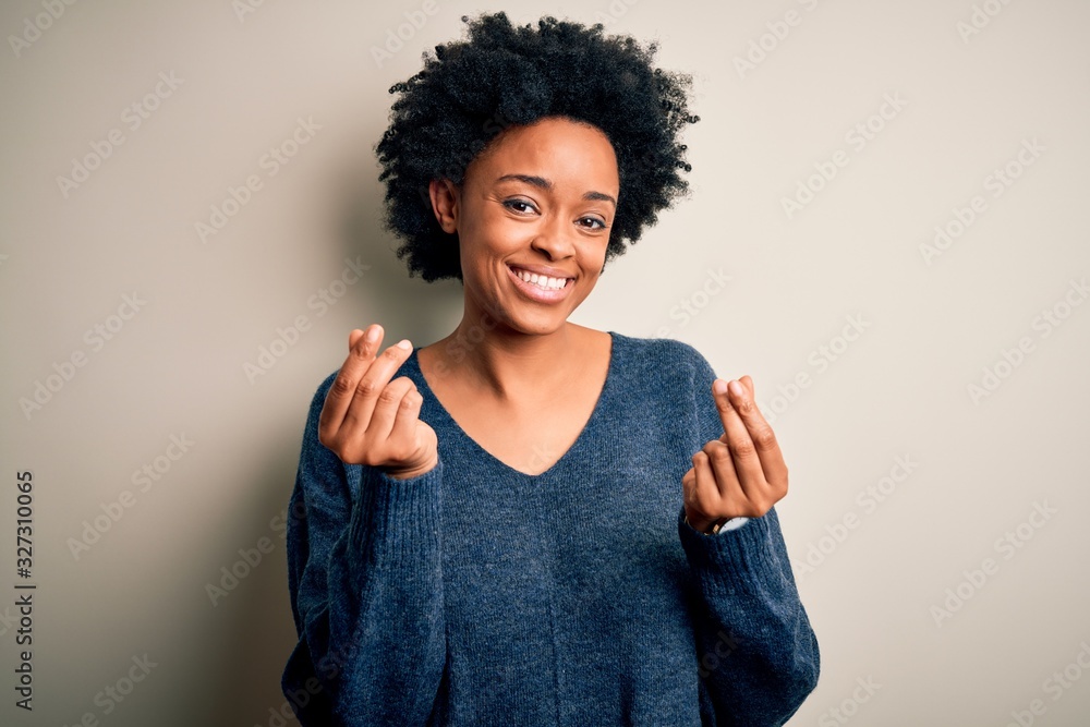 Young beautiful African American afro woman with curly hair wearing casual sweater doing money gesture with hands, asking for salary payment, millionaire business Young beautiful African American afro woman with curly hair wearing casual sweater doing money gesture with hands, asking for salary payment, millionaire business