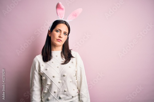 Young caucasian woman wearing cute easter rabbit ears over pink isolated background Relaxed with serious expression on face. Simple and natural looking at the camera.