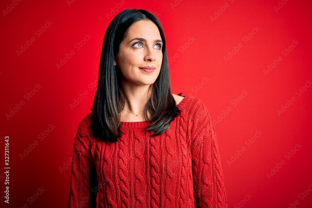 Young brunette woman with blue eyes wearing casual sweater over isolated red background smiling looking to the side and staring away thinking. Young brunette woman with blue eyes wearing casual sweater over isolated red background smiling looking to the side and staring away thinking.
