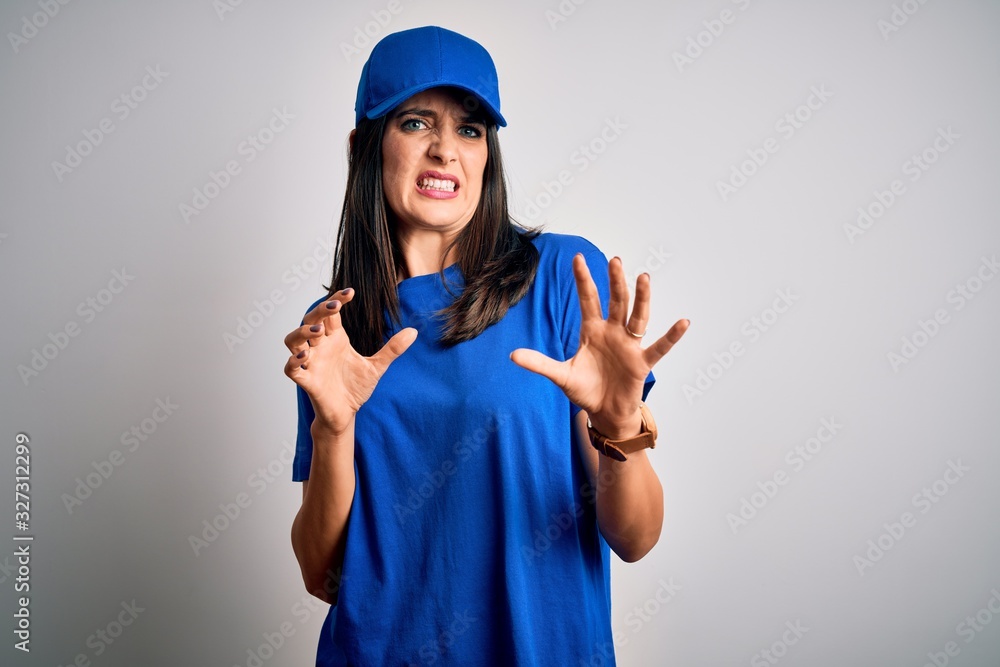 Young delivery woman with blue eyes wearing cap standing over blue background disgusted expression, displeased and fearful doing disgust face because aversion reaction. With hands raised Young delivery woman with blue eyes wearing cap standing over blue background disgusted expression, displeased and fearful doing disgust face because aversion reaction. With hands raised