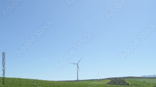 Wind turbine moving the blades in a field a sunny day with blue sky photo