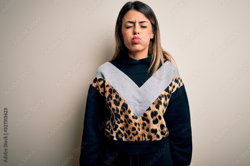 Young beautiful woman wearing casual sweatshirt standing over isolated white background puffing cheeks with funny face. Mouth inflated with air, crazy expression. Young beautiful woman wearing casual sweatshirt standing over isolated white background puffing cheeks with funny face. Mouth inflated with air, crazy expression.