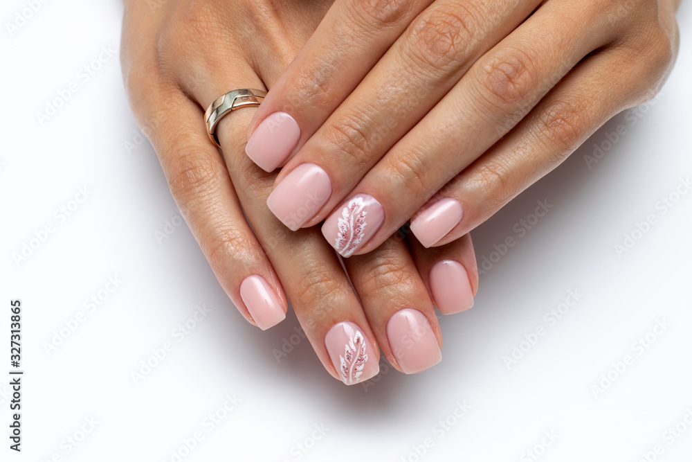 Close-up of pink manicure with a painted white feather on short square nails on a white background. Nude manicure. Beige, Body, Natural nails. Close-up of pink manicure with a painted white feather on short square nails on a white background. Nude manicure. Beige, Body, Natural nails.