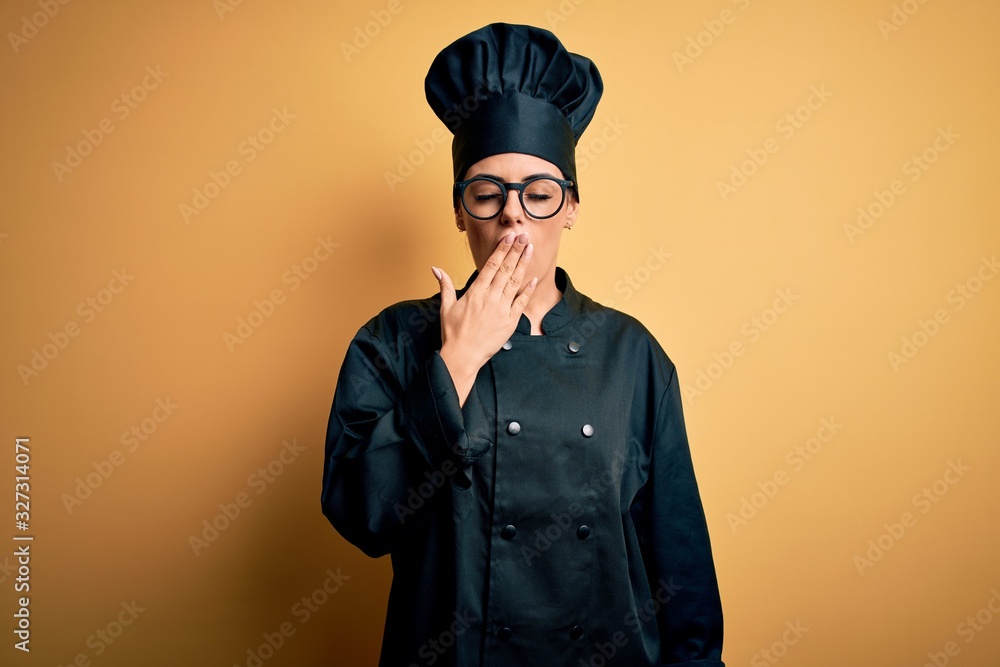 Young beautiful brunette chef woman wearing cooker uniform and hat over yellow background bored yawning tired covering mouth with hand. Restless and sleepiness. Young beautiful brunette chef woman wearing cooker uniform and hat over yellow background bored yawning tired covering mouth with hand. Restless and sleepiness.