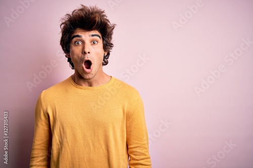 Young handsome man wearing yellow casual t-shirt standing over isolated pink background afraid and shocked with surprise expression, fear and excited face. © Krakenimages.com