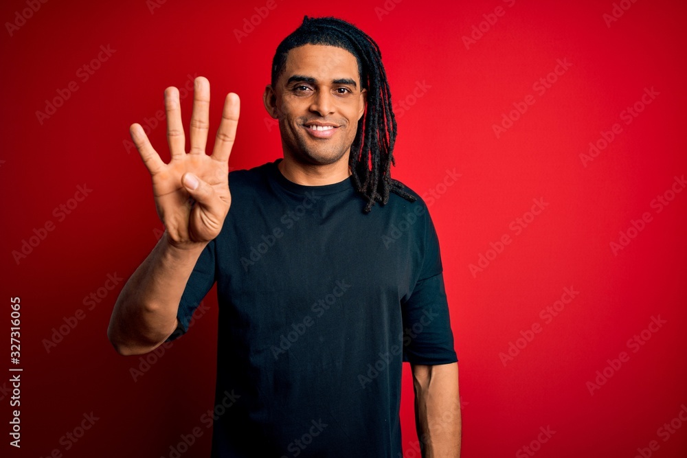 Young handsome african american afro man with dreadlocks wearing casual t-shirt showing and pointing up with fingers number four while smiling confident and happy. Young handsome african american afro man with dreadlocks wearing casual t-shirt showing and pointing up with fingers number four while smiling confident and happy.