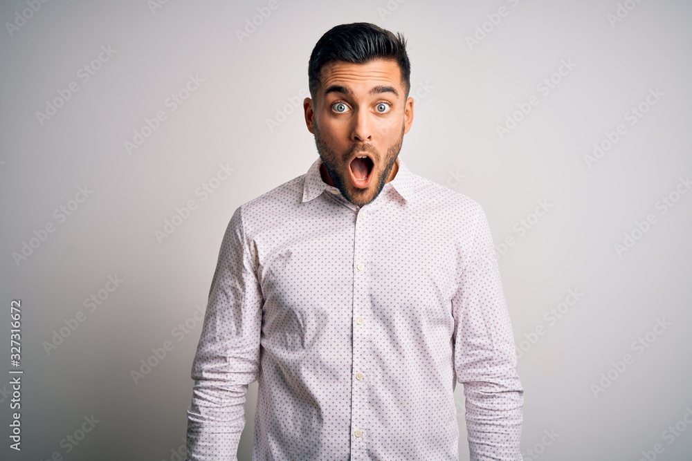 Young handsome man wearing elegant shirt standing over isolated white background afraid and shocked with surprise and amazed expression, fear and excited face. Young handsome man wearing elegant shirt standing over isolated white background afraid and shocked with surprise and amazed expression, fear and excited face.