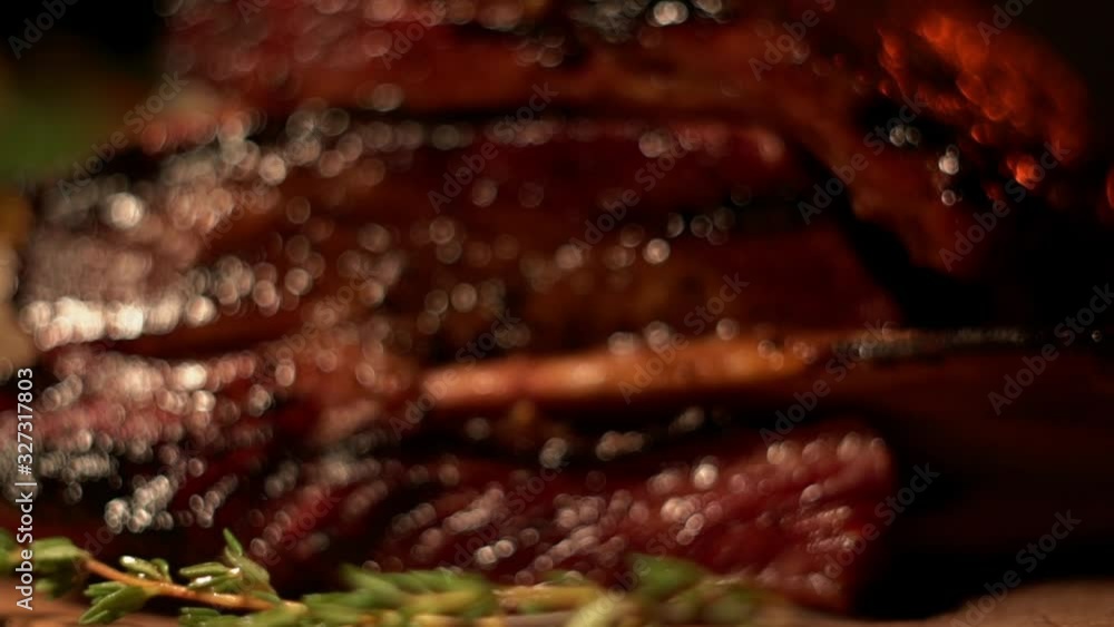 A huge grilled beef rib on a wooden cutting board under warm muffled light, close-up. A massive piece of meat on a bone with potato wedges garnish and greens. A huge grilled beef rib on a wooden cutting board under warm muffled light, close-up. A massive piece of meat on a bone with potato wedges garnish and greens.